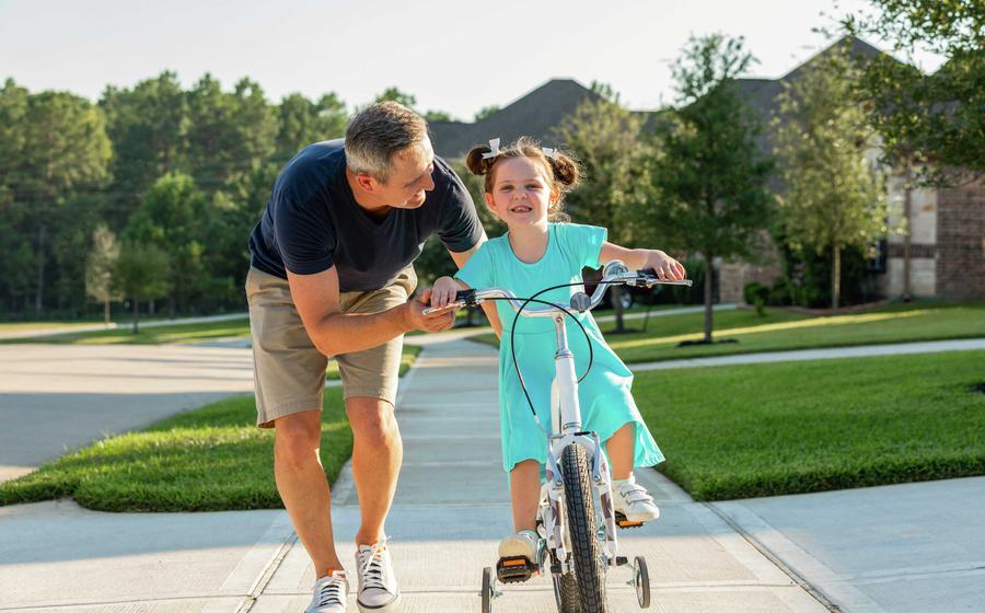 Dad and daughter on bicycle.