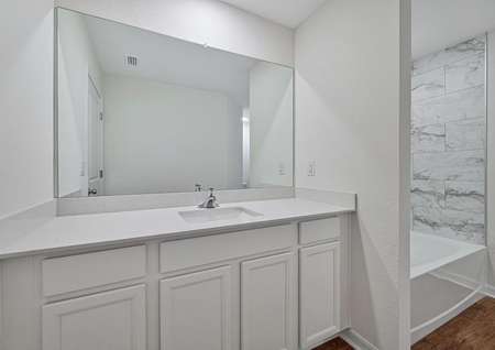 The bathroom has a spacious vanity and beautiful tiled tub