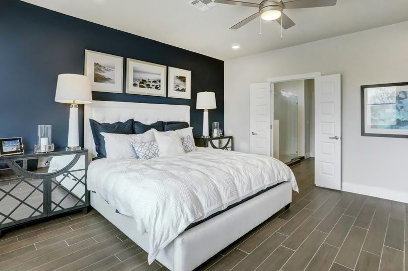 Staged bedroom with a white bed and dark blue accent wall.