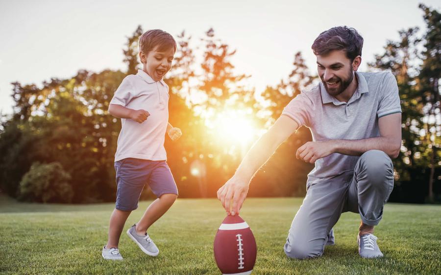 Father and son playing football in field.
