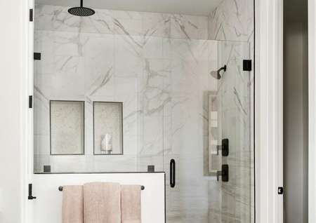 Beautiful, large step-in shower with tiled marble walls and black hardware accents