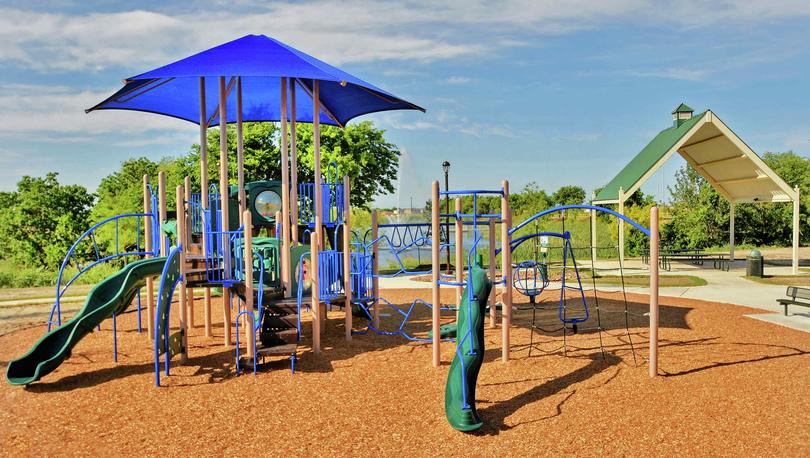 Luckey Ranch new home community children's playground with wood chips and blue umbrella for shade
