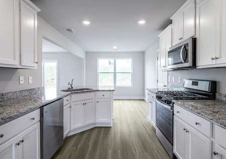 Kitchen with stainless appliances, vinyl floors and white cabinets.