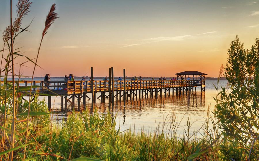 Kure Beach, North Carolina Fort Fisher Air Force Recreation Center at sunset with long wooden pier, water, and plants