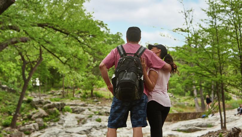 Couple hiking with lake and trees in the background.