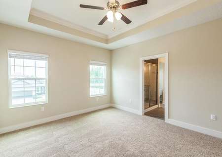 Secluded primary bedroom featuring a vaulted ceiling with a fan, two windows and its own full bathroom with a walk-in closet.