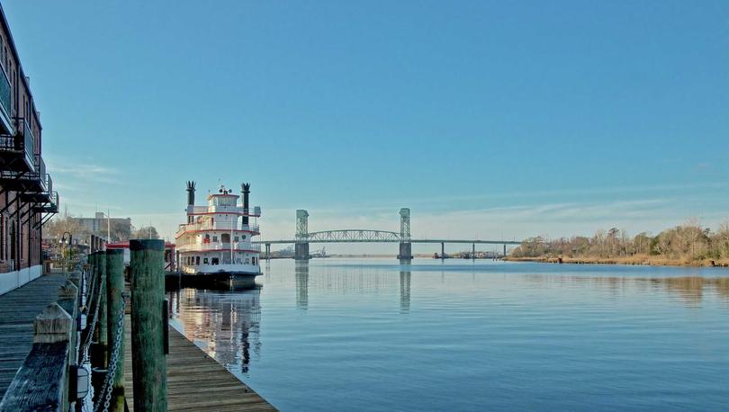 Wilmington, North Carolina Riverfront with large boat, river, and bridge in the background