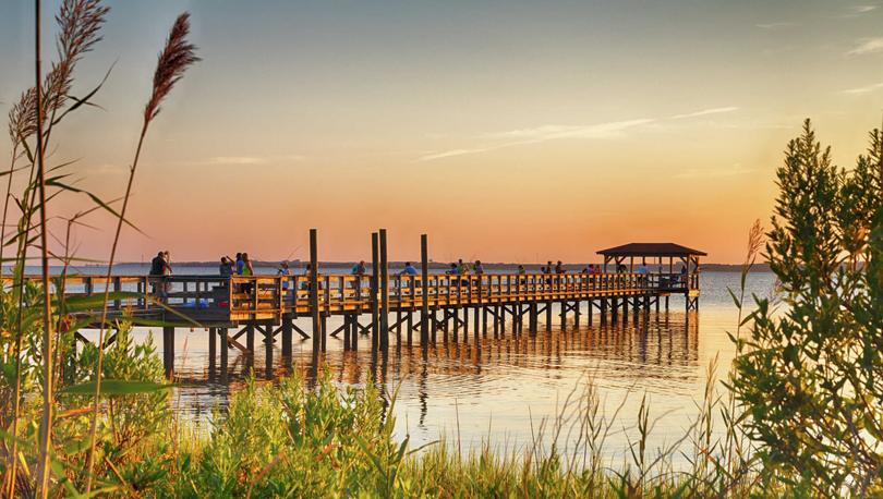 Kure Beach, North Carolina Fort Fisher Air Force Recreation Center at sunset with long wooden pier, water, and plants