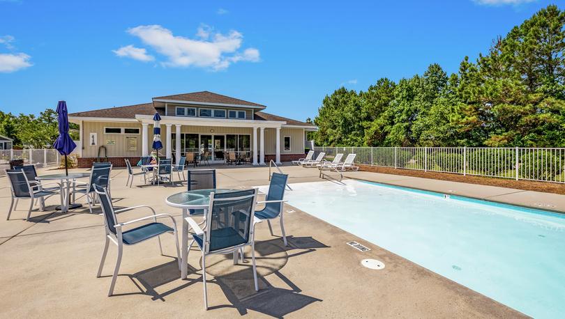 Swimming pool and clubhouse with lounge furniture.