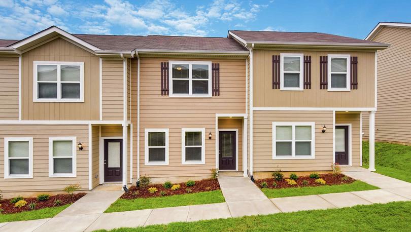 Exterior view of the Anderson 2 story, single family attached home with tan siding and white trim, shingle roofing, shutters adorning the upper windows, and landscaped front yard