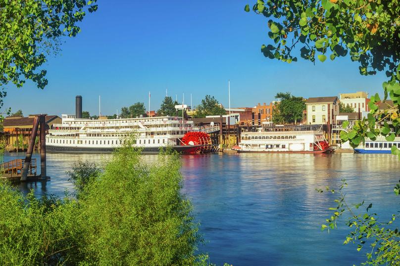 Sacramento, California Historic Old Town site waterfront with riverboats, greenery, and houses in the background