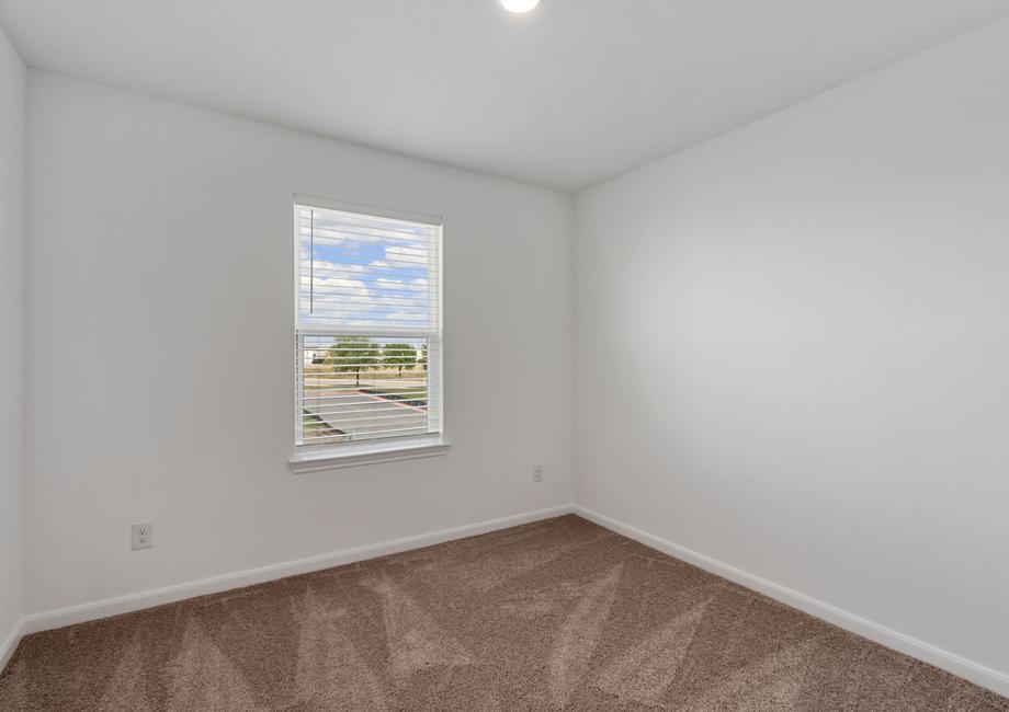 Secondary bedroom with a window and tan carpet.