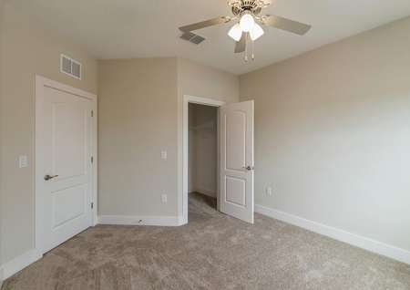 Spacious, carpeted bedroom with a ceiling fan and a large walk-in closet.