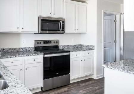 Kitchen with granite countertops, white cabinets and stainless steel appliances.