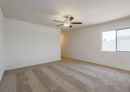 Open family room with tan carpet and a ceiling fan.