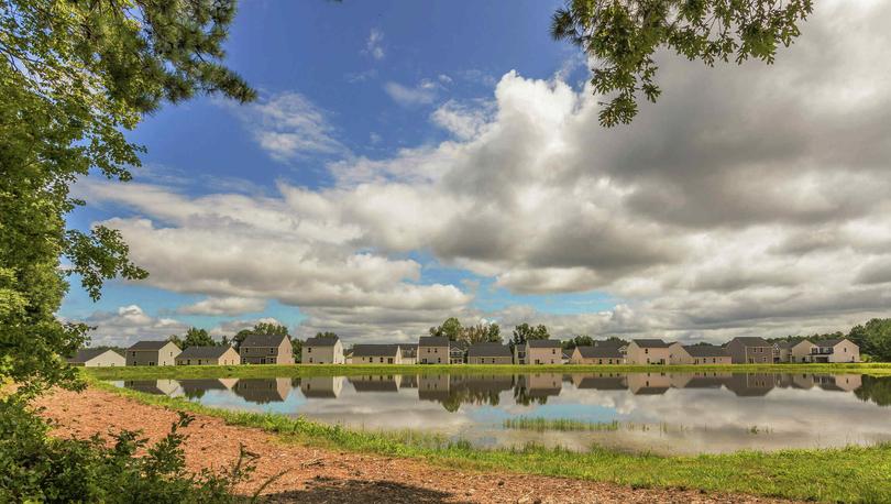 View of the lake in the Autumn Lakes community with the homes and clouds in the background.