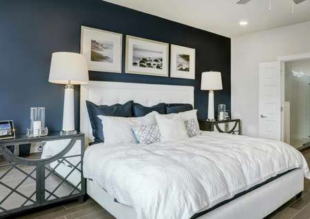 Staged bedroom with a white bed and dark blue accent wall.