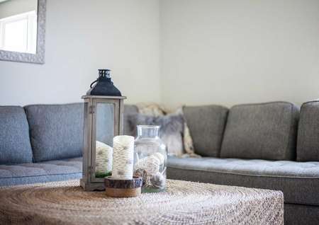 Driftwood staged living room with grey couch and white colored coffee table with vase and candle sitting on it