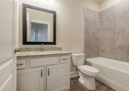 Full bathroom with a granite countertop sink and modern hardware.