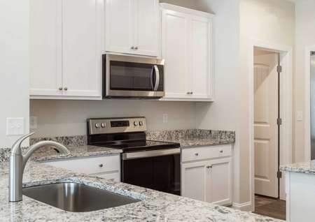 Alamance kitchen with light color granite counters, white cabinets, and undermounted sink