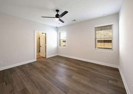 Master bedroom with a ceiling fan and plank flooring