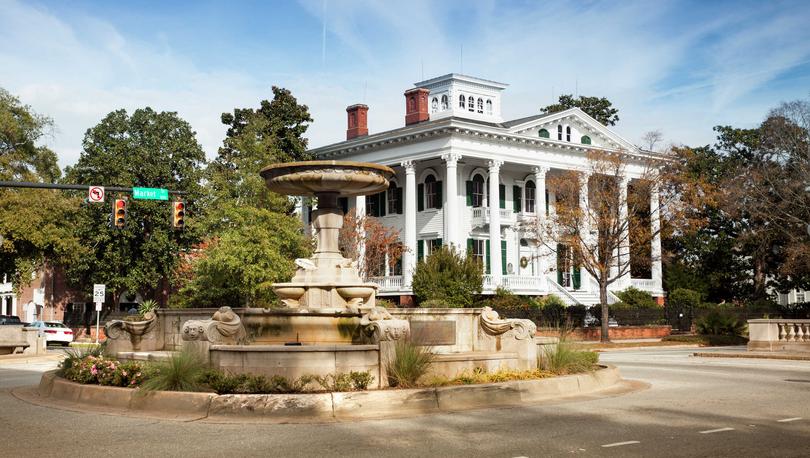 Wilmington North Carolina, The Bellamy Mansion with waterless water fountain, large white Colonial building, and overgrown trees