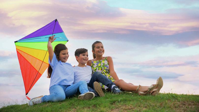 Kids in the park with a kite at sunset.