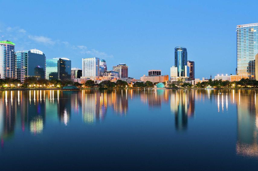 Orlando, Florida skyline at sunrise from Lake Eola showing calm waters and large office buildings reflecting in the water