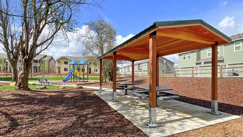 Photo of neighborhood park with a picnic gazebo, playground, sidewalks and benches.