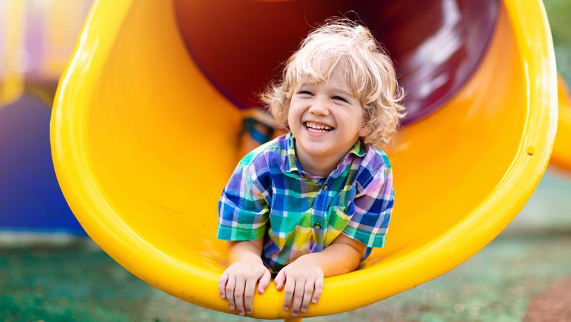 Little boy smiling in a playground.