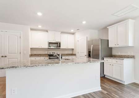 Kitchen with white cabinets, granite countertops and stainless steel appliances.