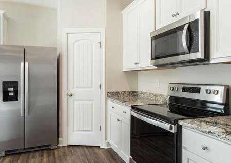 Avery kitchen with dual-door stainless steel refrigerator, granite counters, and walk-in pantry