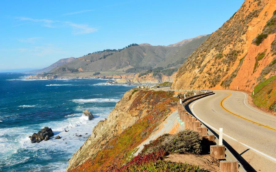 Bay Area, California Highway 1 running alongside the Pacific Ocean in Big Sur State Park showing windy coastal roads, waves crashing into cliffs, and blue skies