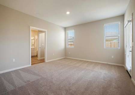 The spacious master suite has light brown carpet, tan walls and access to the master bath.