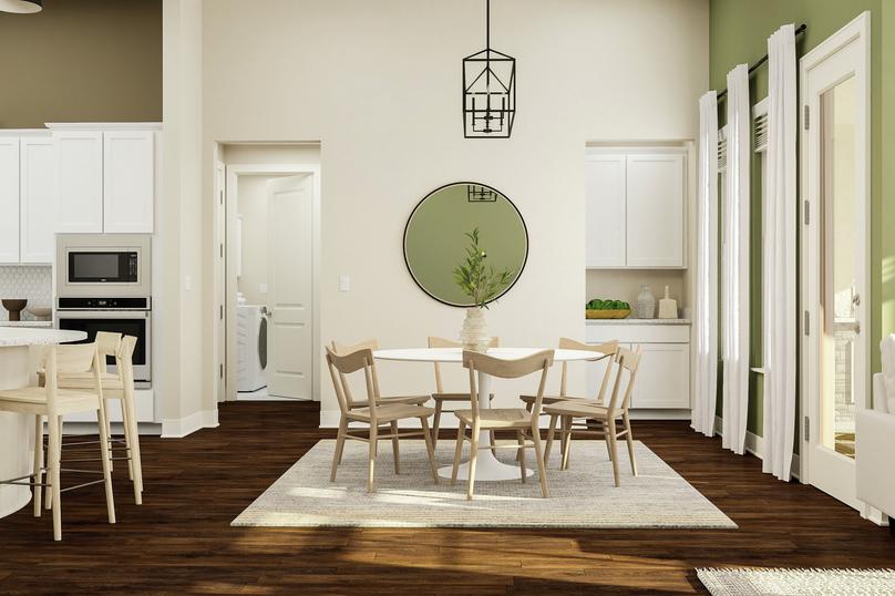 Rendering of a dining space showing a
  round table and chairs under a black light fixture on a white rug, with
  cabinetry and laundry room in the background and dark wood look flooring
  throughout.