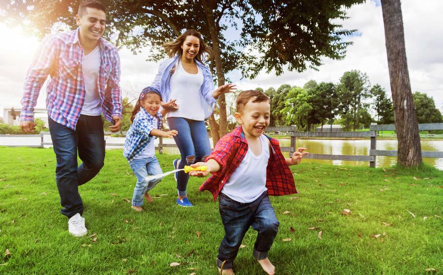 A family of four running near a pond.