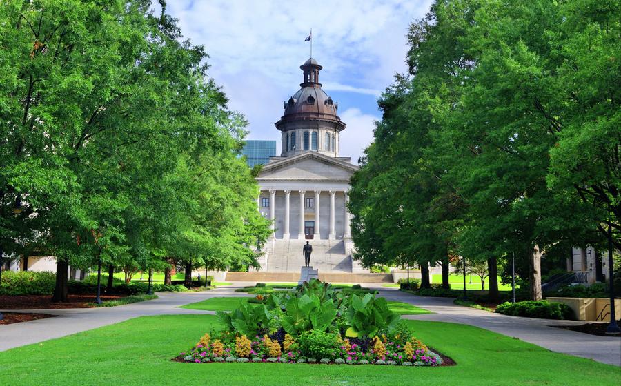 Columbia, South Carolina State Capitol building with bronze cupola, grey stonework, and green landscaped grounds