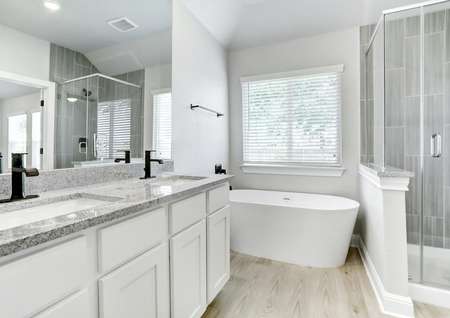 Exquisite master bathroom with gorgeous granite countertops, white cabinets, a soaking tub, and walk-in shower.