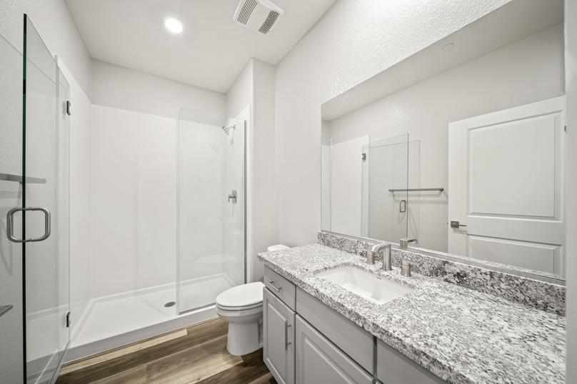 Secondary bathroom with a walk-in shower, granite countertops, and white cabinets.