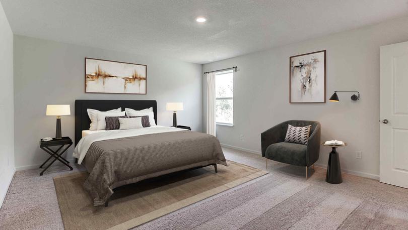 Staged serene master bedroom with queen bed, two nightstands with lamps, chair with art and wall lamp, one window near corner.
