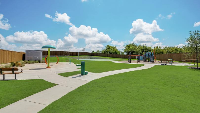 Overall view of the community park with a splash pad, playground and basketball court.