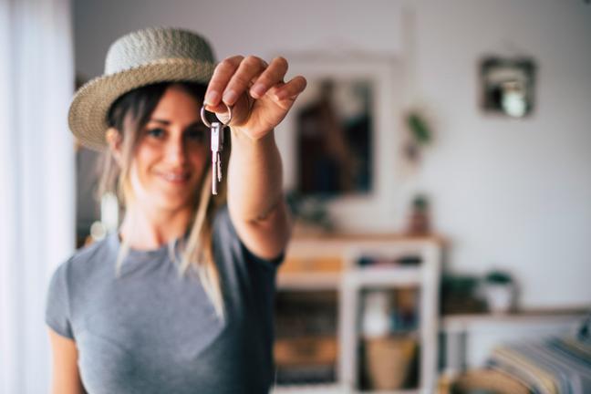 A young woman holds up her keys.