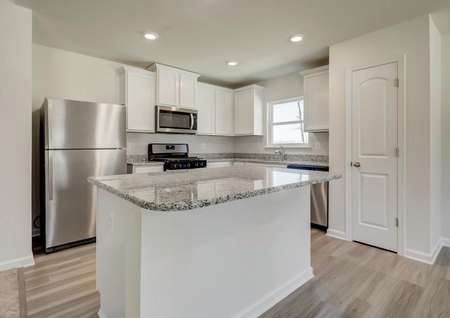 Modern kitchen with white cabinets, polished gray granite, stainless appliances, recessed lighting, window.