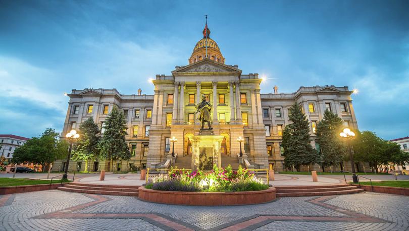 Denver, Colorado Capitol building with star-shaped brick driveway, landscaped grounds, and lit stone facade