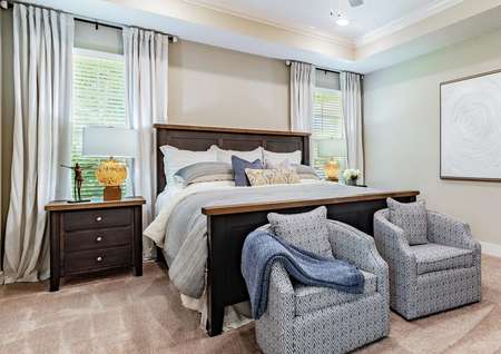 Staged master bedroom with two blue chairs and a blue bed.