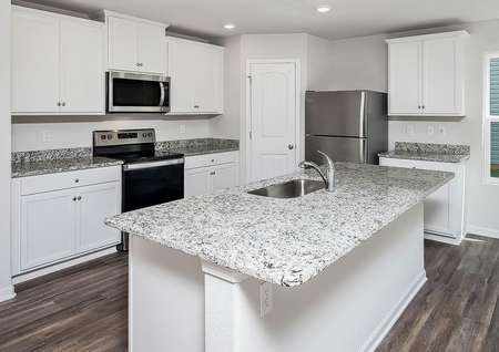 Kitchen with granite countertops, white cabinets with hardware, stainless steel appliances and vinyl flooring. 