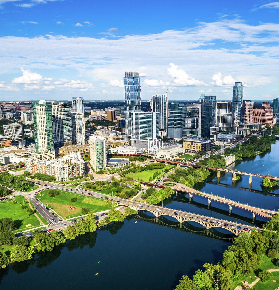 Austin, Texas cityscape taken just before sunset showing a panoramic view of the city's skyscrapers, the river flowing down the Colorado, and green parks
