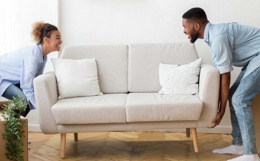 Couple moving couch into their new home. 