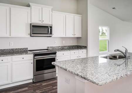 Chef-ready kitchen with granite countertops, white cabinetry with hardware, stainless steel appliances and vinyl flooring. 