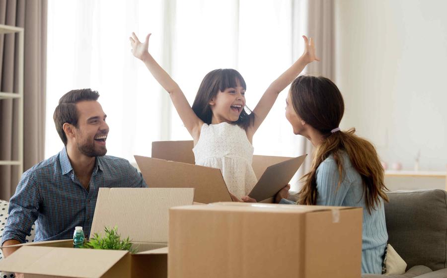 Family unpacking boxes, happy girl with arms in air